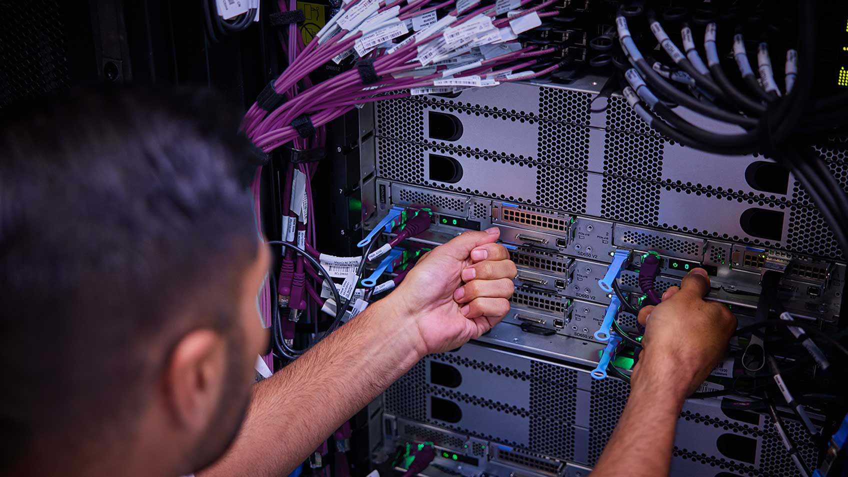 A man plugging cords into a server