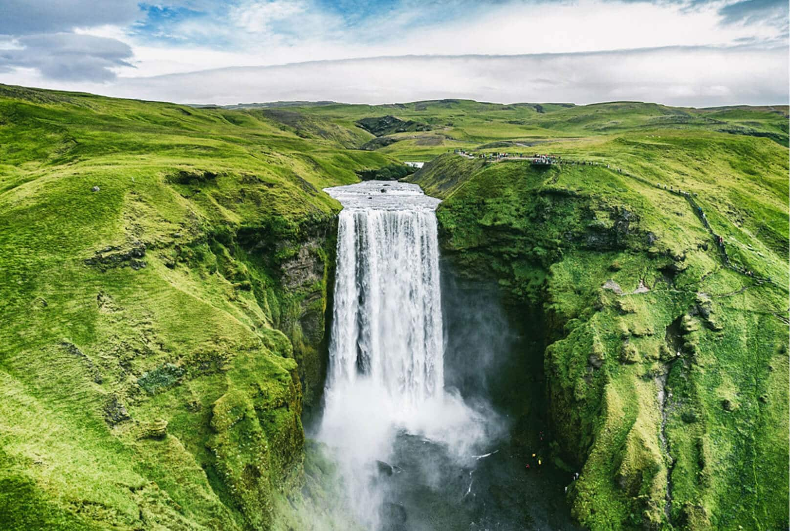 Une montagne verte et luxuriante avec une chute d’eau en cascade au centre de celle-ci