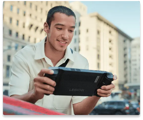 Фотография молодого человека, играющего на Legion Go, на фоне города