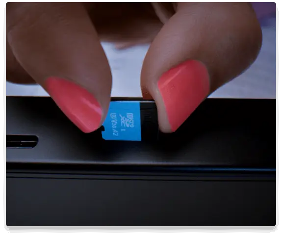 Legion Go'nun mini SD yuvasına mini SD kart takan bir kişinin yakın çekim görüntüsü
