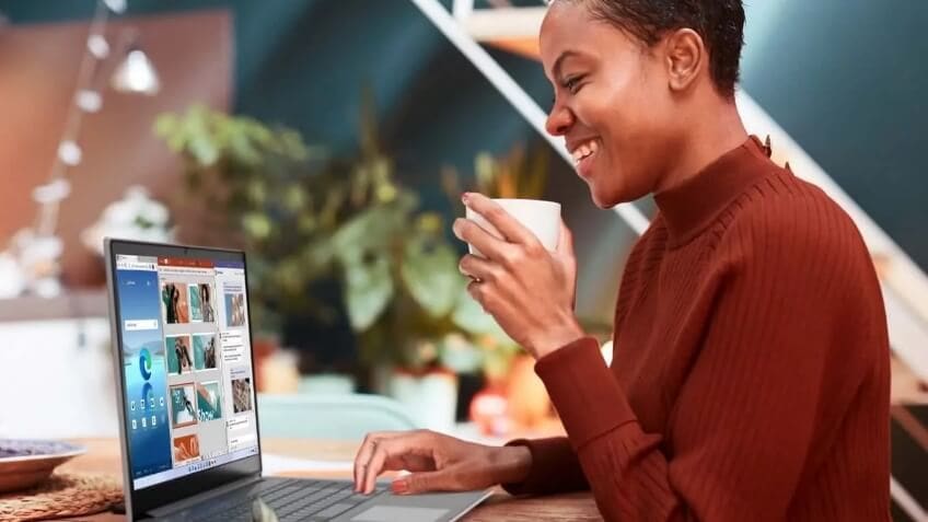 Woman working on a laptop, drinking from a coffee cup.