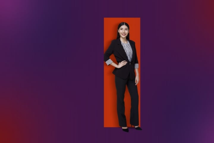 A confident woman in a suit against a bold red and purple gradient background.