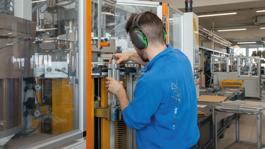 Technician adjusts industrial machinery on a modern factory floor.