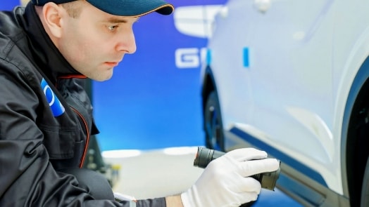 Close-up image of a race car driver inspecting a car.