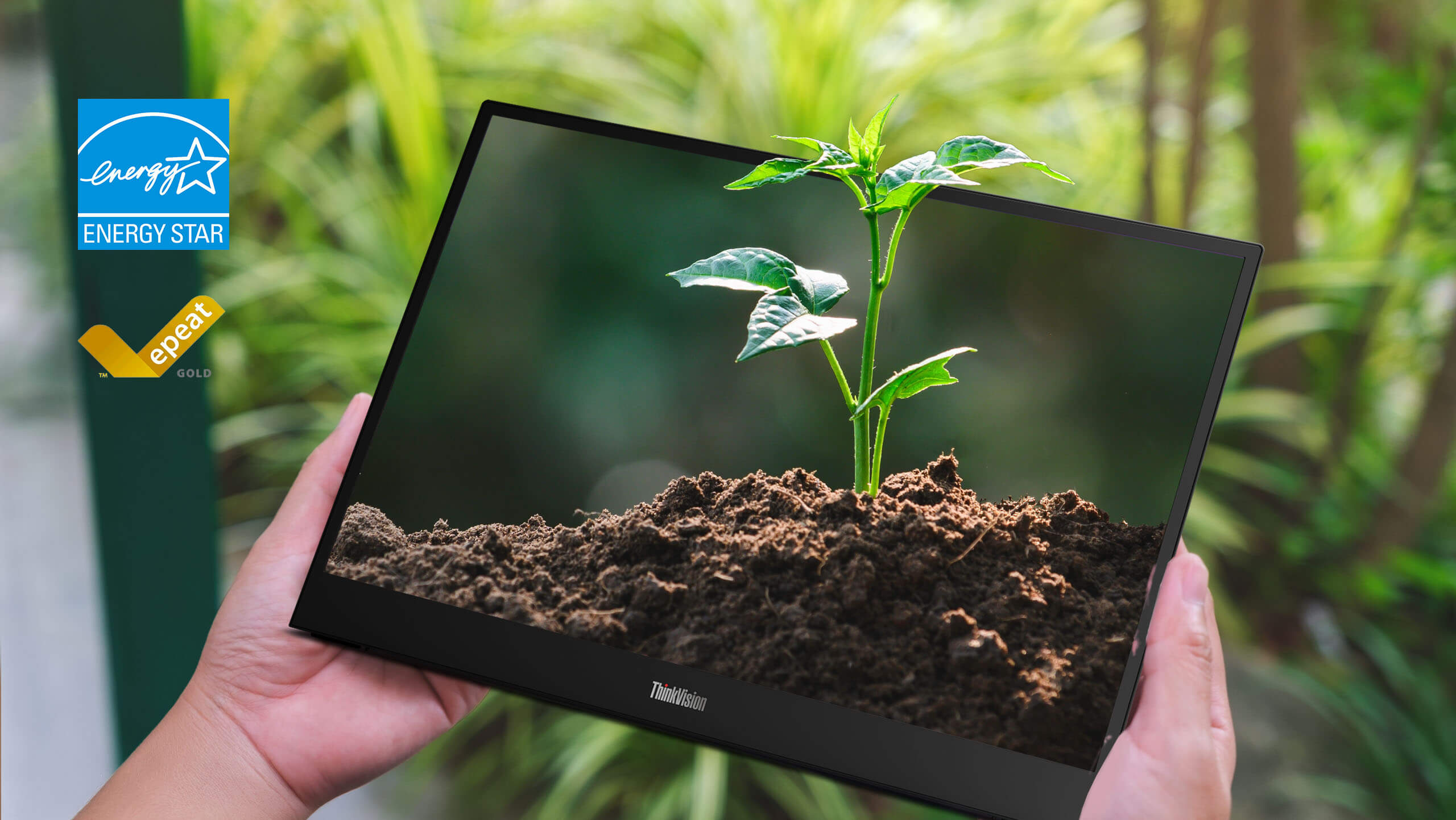 Person holding a thin monitor displaying a thriving plant in soil, symbolizing eco-friendliness. Energy Star and EPEAT Gold logos are visible.