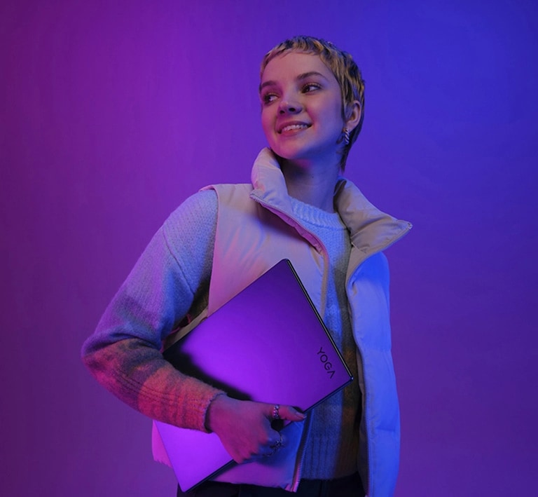 A young female with a Lenovo Yoga under her arm, under violet light