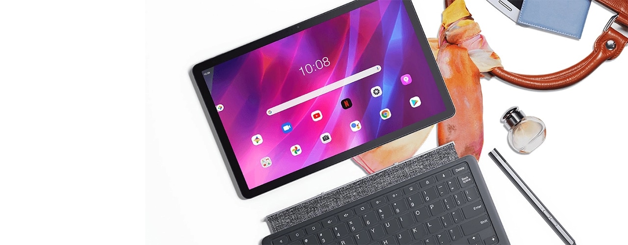 Lenovo Tab P11 Plus tablet—front view with home screen and multiple app icons on the display, plus optional keyboard and pen, all on top of handbag and scarf, with several personal items strewn about
