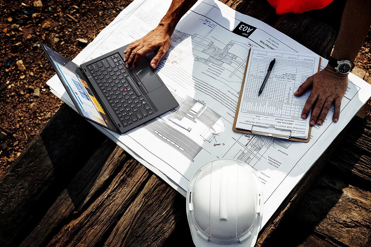 Lenovo ThinkPad X1 Carbon (6th Gen) overhead shot, used in conjunction with a contractor's report outdoors.