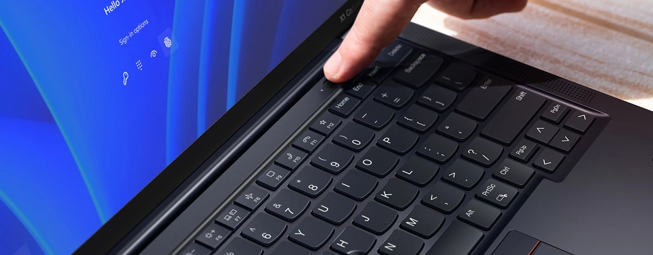 Detailansicht eines Fingers, der den An/Aus-Schalter mit integriertem Fingerabdruckscanner am Lenovo ThinkPad X1 Carbon Gen 11 Notebook berührt.
