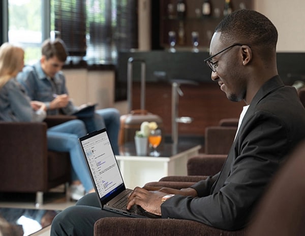 A man, facing left, types on a ThinkPad X13 Gen 4 laptop that’s resting on his lap