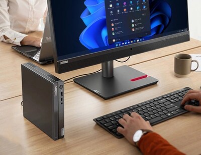 Primer plano del Lenovo ThinkCentre Neo 50q de 4.ª generación Tiny (Intel), colocado verticalmente sobre un escritorio de oficina, junto a un monitor y un teclado (vendidos por separado), con una persona escribiendo en el teclado